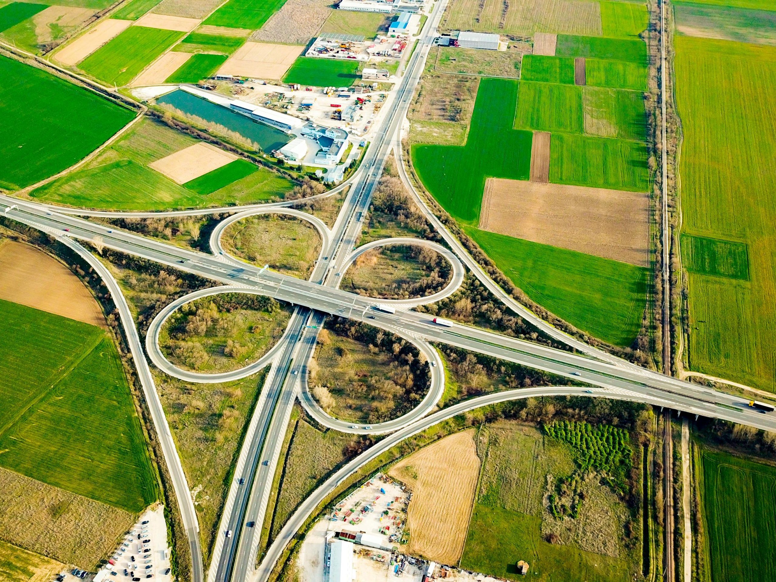 Aerial shot of a highway interchange surrounded by vibrant green fields.